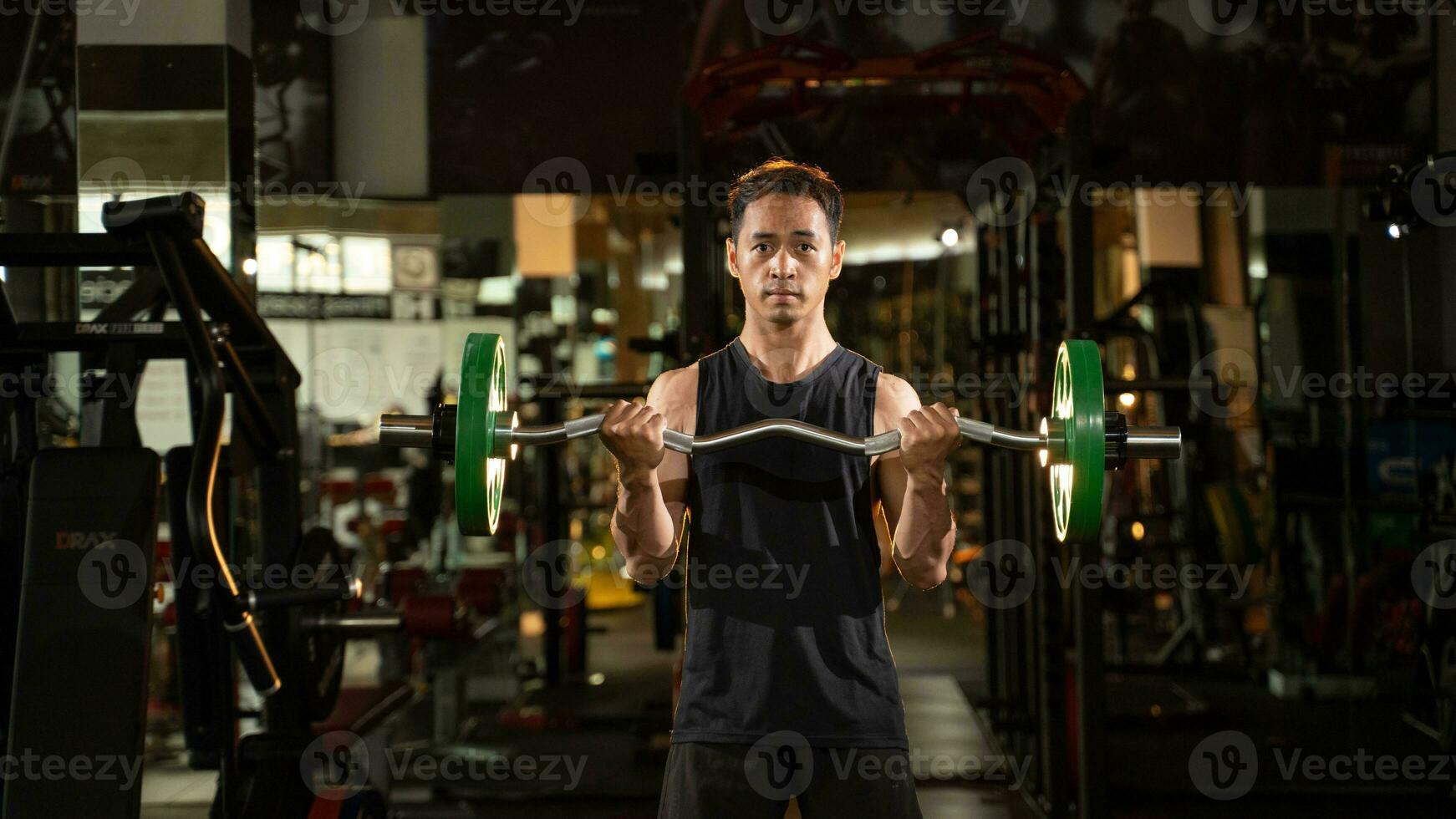 un retrato de un masculino levantador de pesas en negro ropa de deporte. él lo hace barra con pesas aptitud rutina de ejercicio en el moderno gimnasia. foto