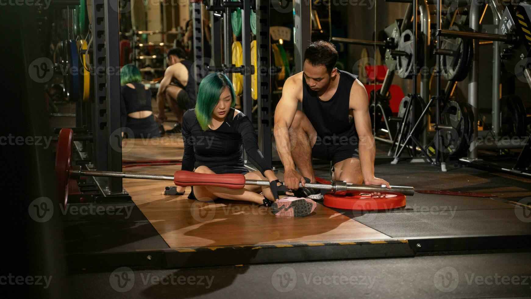 bonito mujer teniendo lesión durante ejercicio en gimnasio mientras entrenador tomando primero ayuda, accidente y deporte aptitud concepto. foto