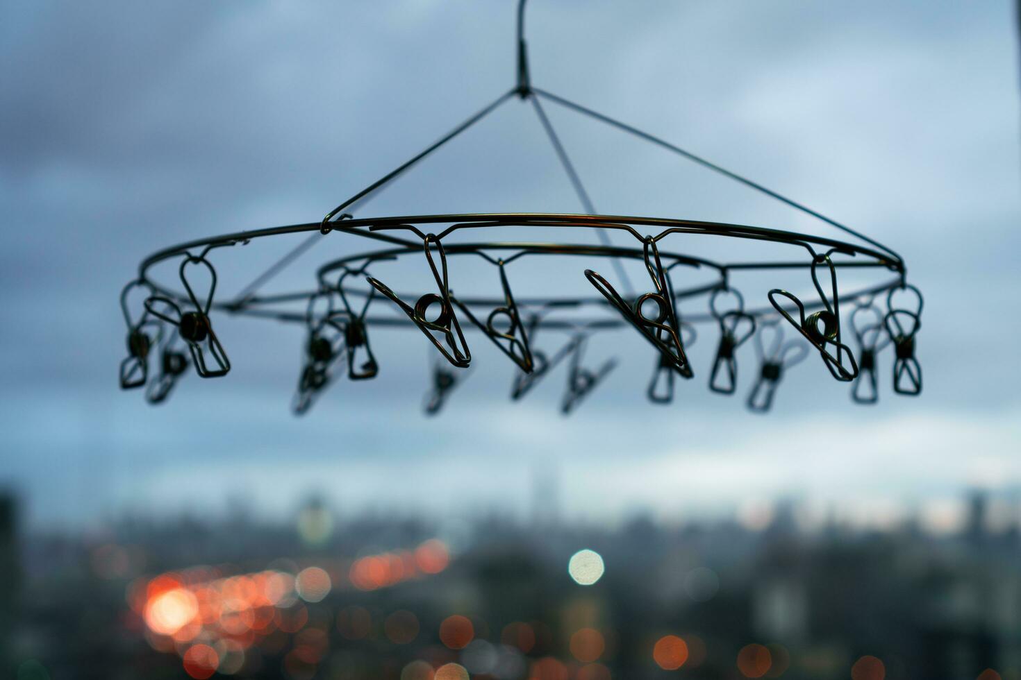 Close up of stainless steel hanging clothespins with blurred background of city in rainy day photo