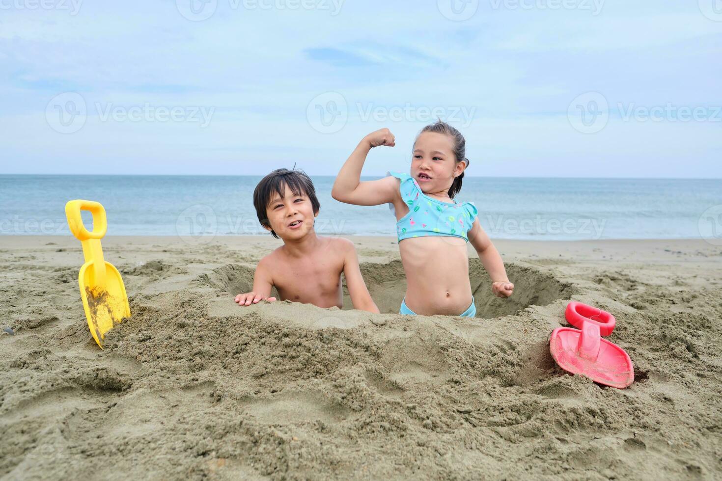 Children dig a hole in the sand on the seashore. photo