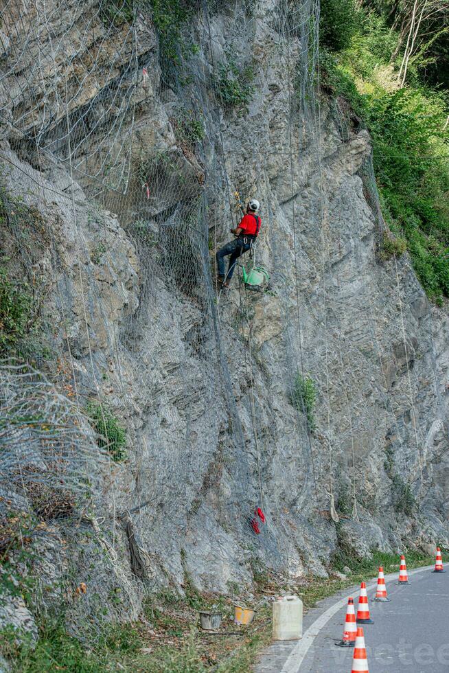 Climber placing safety nets to avoid falling rocks photo