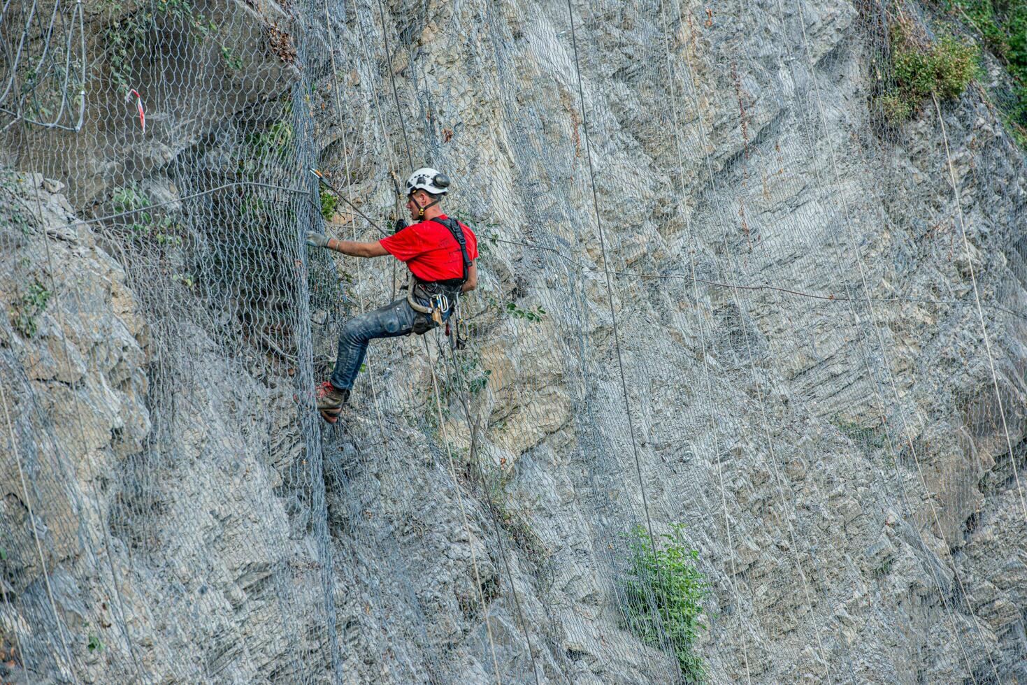 Climber placing safety nets to avoid falling rocks photo