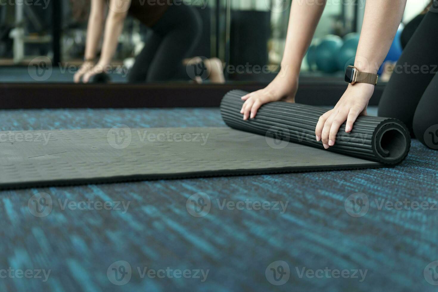 Fitness woman folding exercise mat before working out in yoga studio. rolling Yoga mat  after training healthy lifestyle photo