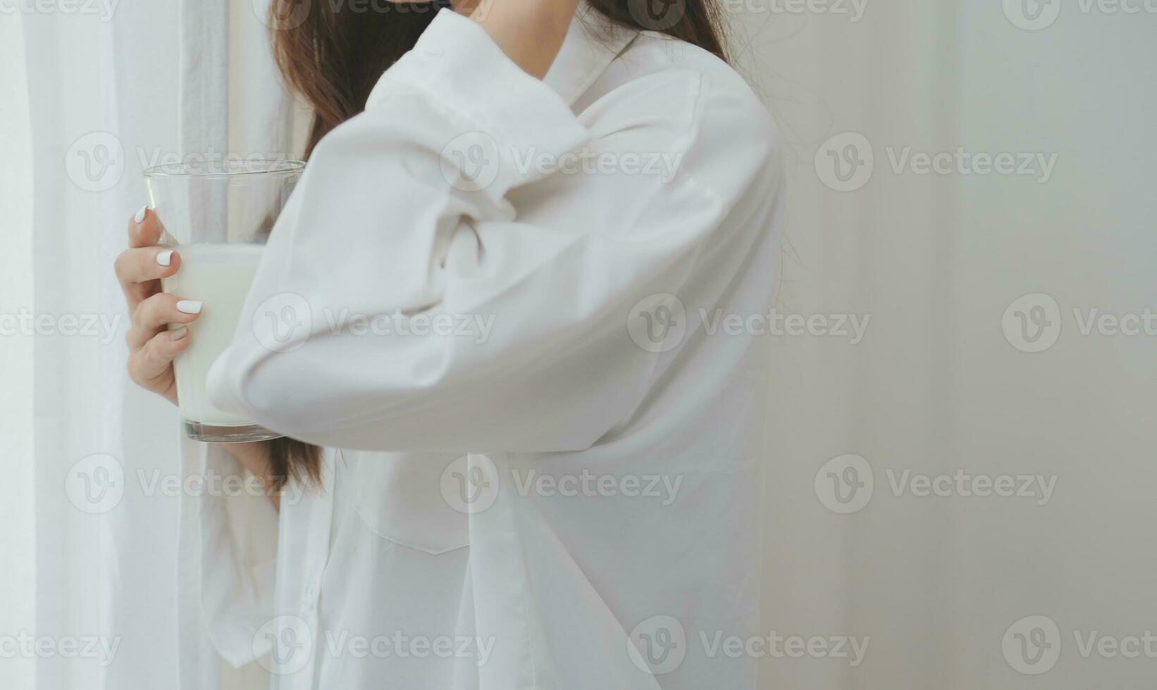 Happy young female in casual clothes smiling and looking at camera while using laptop on bed in bedroom at home photo