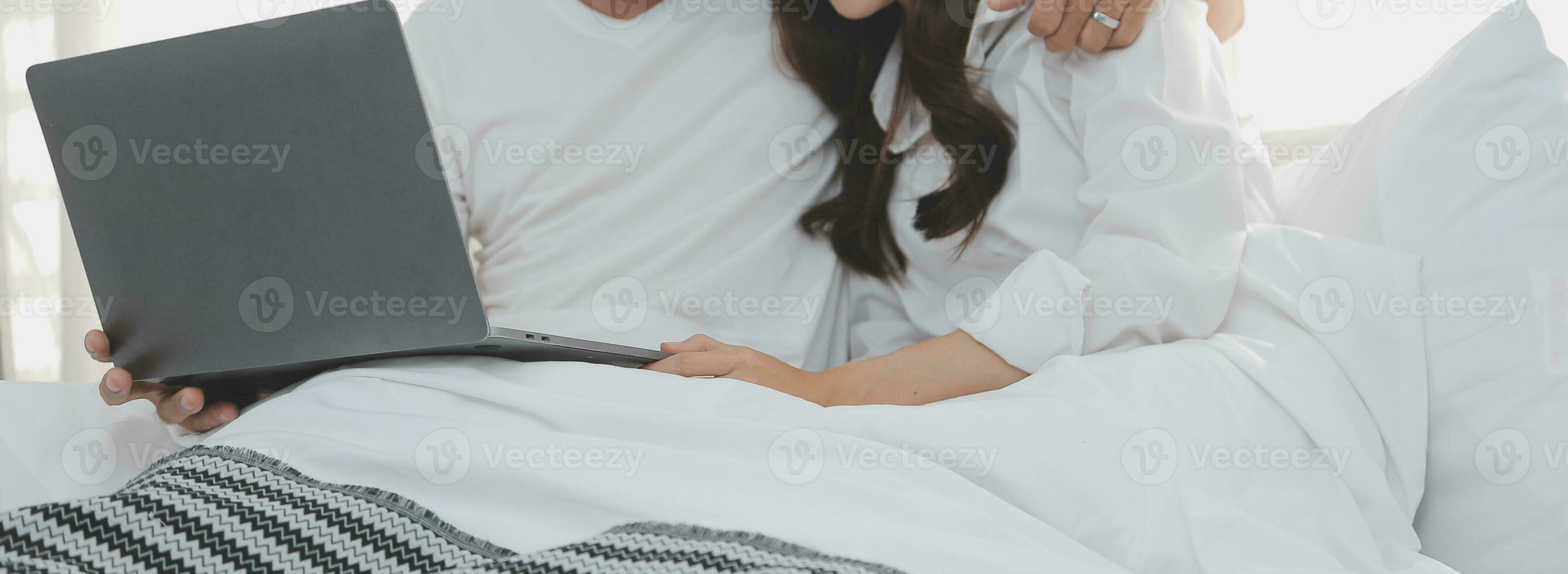 Portrait of young happy couple using laptop at night, using modern technology having fun with glowing screen in dark office or at home, startup business meeting video call distance of young business photo