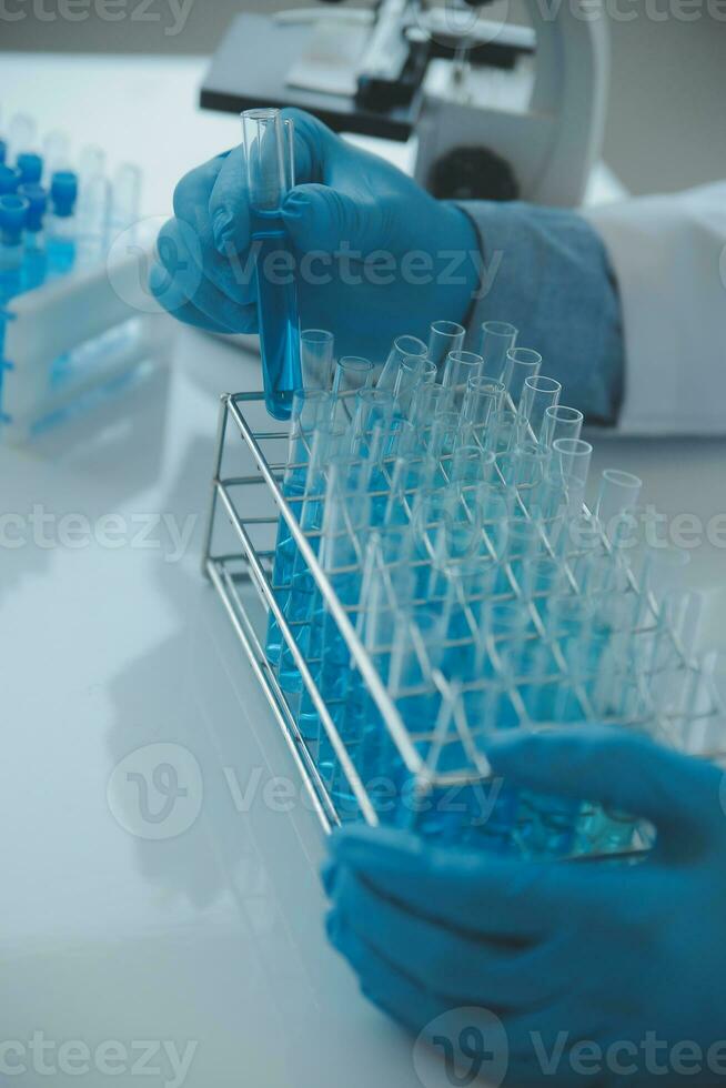 biochemical research scientist team working with microscope for coronavirus vaccine development in pharmaceutical research labolatory, selective focus photo