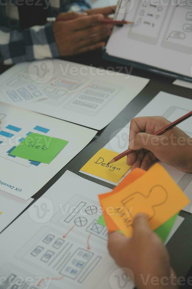 Close up ux developer and ui designer brainstorming about mobile app interface wireframe design on table with customer breif and color code at modern office.Creative digital development agency photo