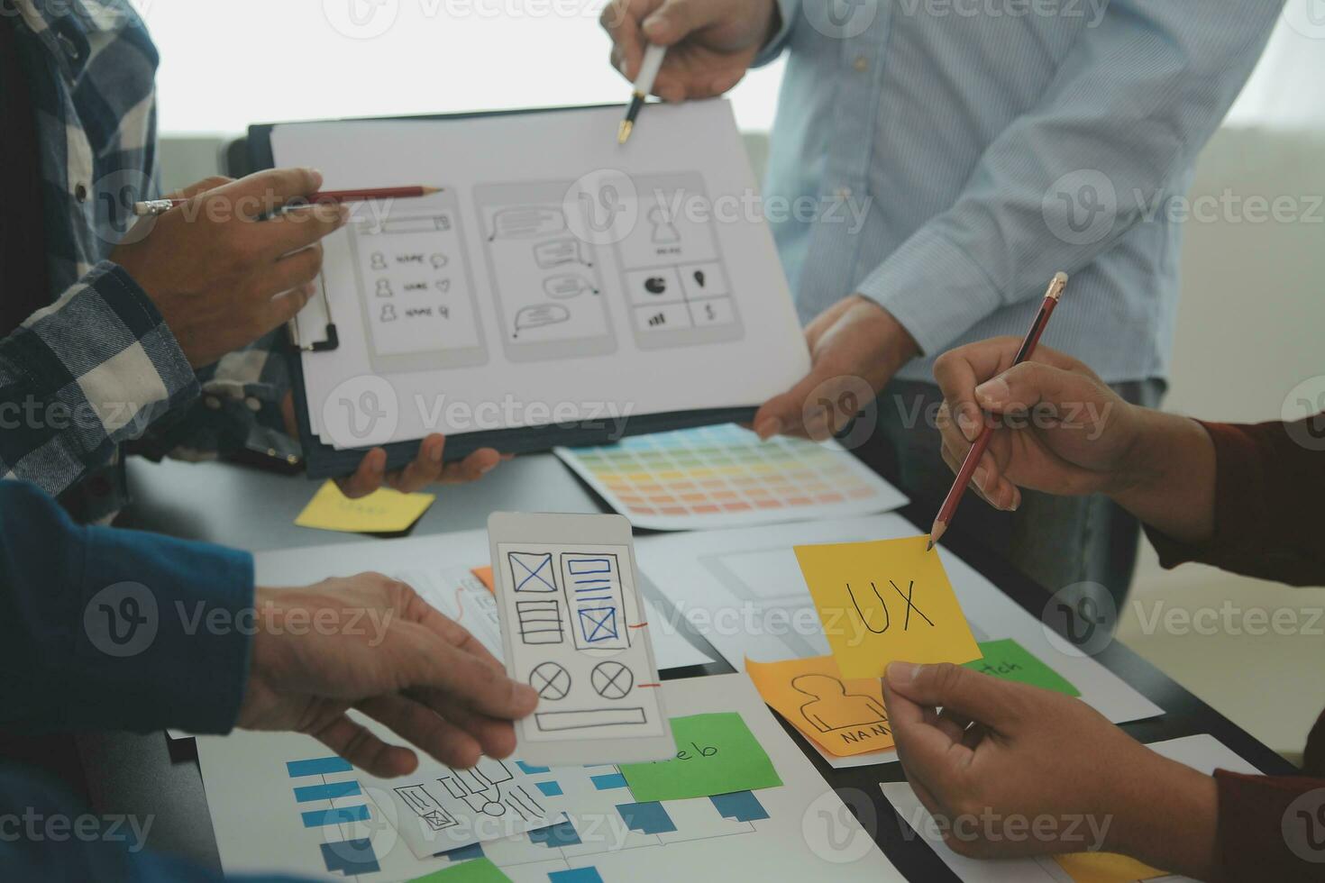 Close up ux developer and ui designer brainstorming about mobile app interface wireframe design on table with customer breif and color code at modern office.Creative digital development agency photo