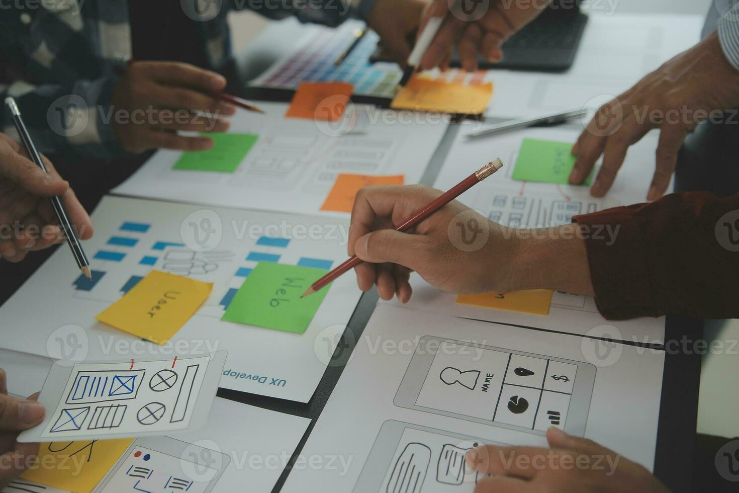 Close up ux developer and ui designer brainstorming about mobile app interface wireframe design on table with customer breif and color code at modern office.Creative digital development agency photo