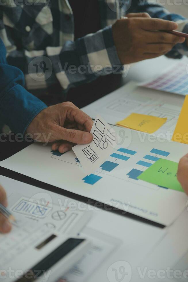 Close up ux developer and ui designer brainstorming about mobile app interface wireframe design on table with customer breif and color code at modern office.Creative digital development agency photo