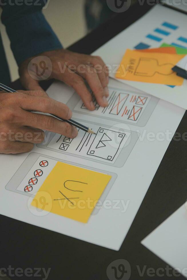 Close up ux developer and ui designer brainstorming about mobile app interface wireframe design on table with customer breif and color code at modern office.Creative digital development agency photo