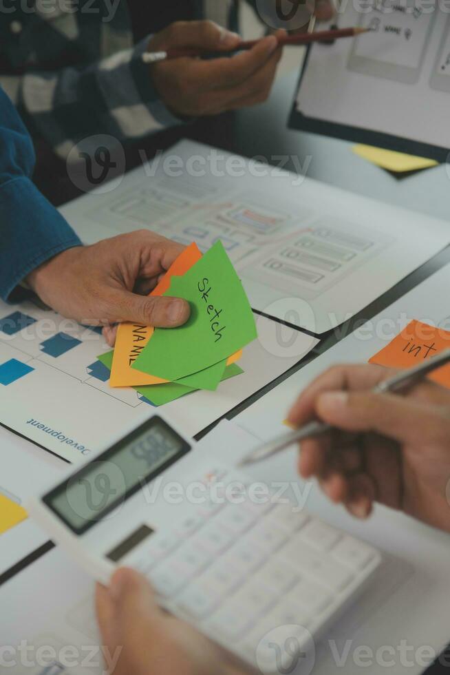 Close up ux developer and ui designer brainstorming about mobile app interface wireframe design on table with customer breif and color code at modern office.Creative digital development agency photo