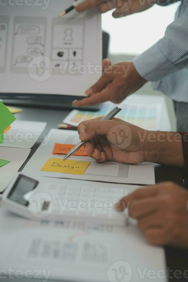 Close up ux developer and ui designer brainstorming about mobile app interface wireframe design on table with customer breif and color code at modern office.Creative digital development agency photo