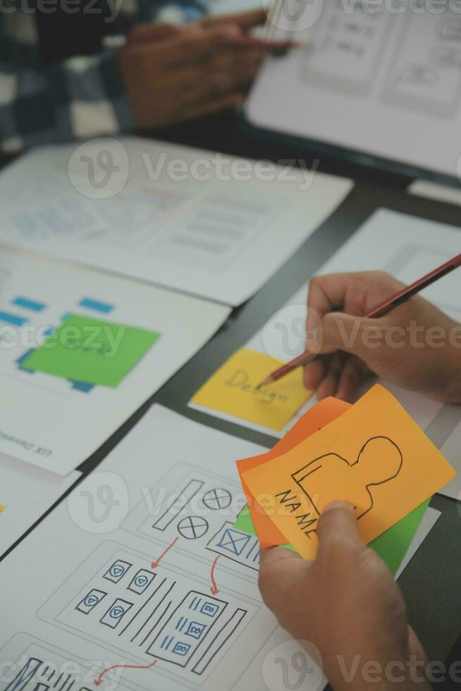 Close up ux developer and ui designer brainstorming about mobile app interface wireframe design on table with customer breif and color code at modern office.Creative digital development agency photo