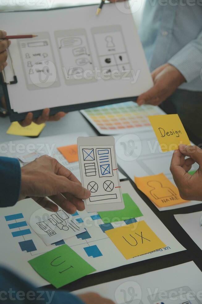 Close up ux developer and ui designer brainstorming about mobile app interface wireframe design on table with customer breif and color code at modern office.Creative digital development agency photo