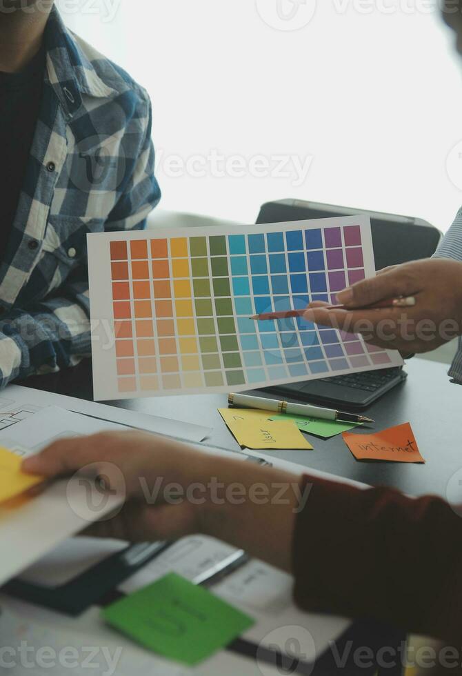 Close up ux developer and ui designer brainstorming about mobile app interface wireframe design on table with customer breif and color code at modern office.Creative digital development agency photo