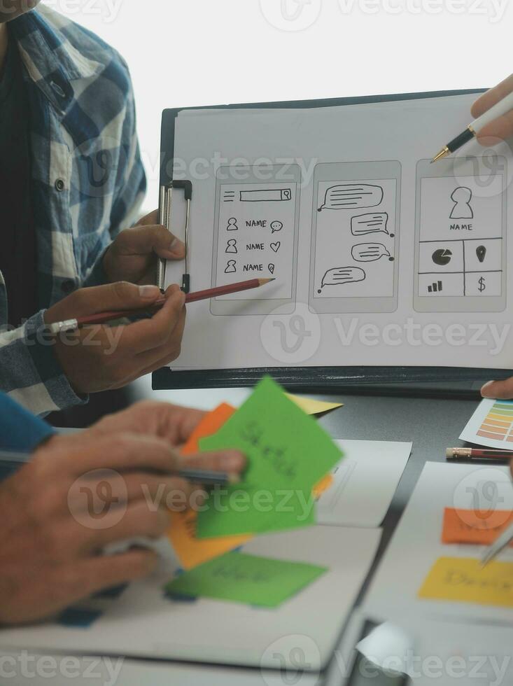 Close up ux developer and ui designer brainstorming about mobile app interface wireframe design on table with customer breif and color code at modern office.Creative digital development agency photo