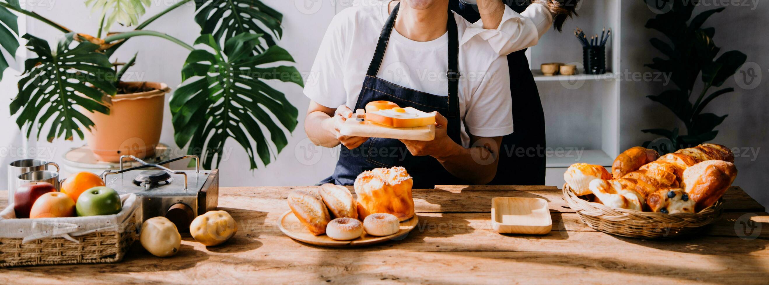 Happy young adult couple making breakfast and drinking coffee together in cozy home kitchen in morning at home. Preparing meal and smiling. Lifestyle, leisure and Love concept. photo