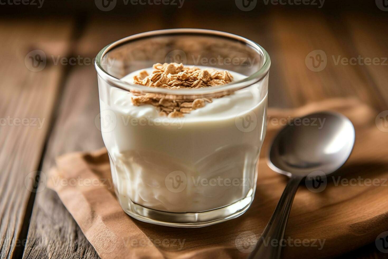 Yogurt in glass with spoon on wooden background photo