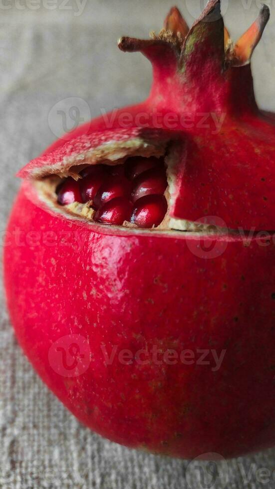 Red pomegranate fruit on canvas. Whole fruit and its grains. Square format. photo