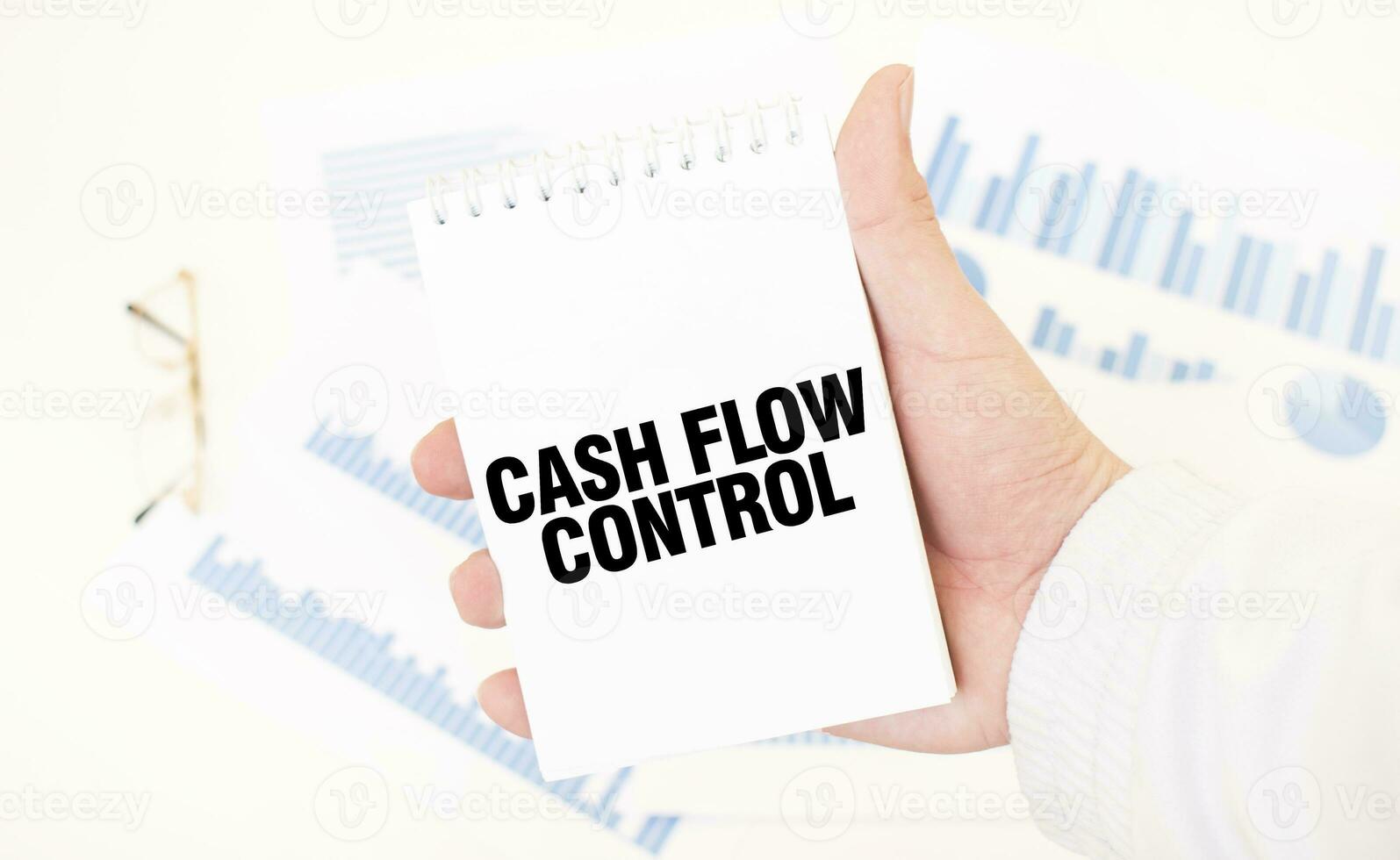 Businessman holding a white notepad with text CASH FLOW CONTROL, business concept photo