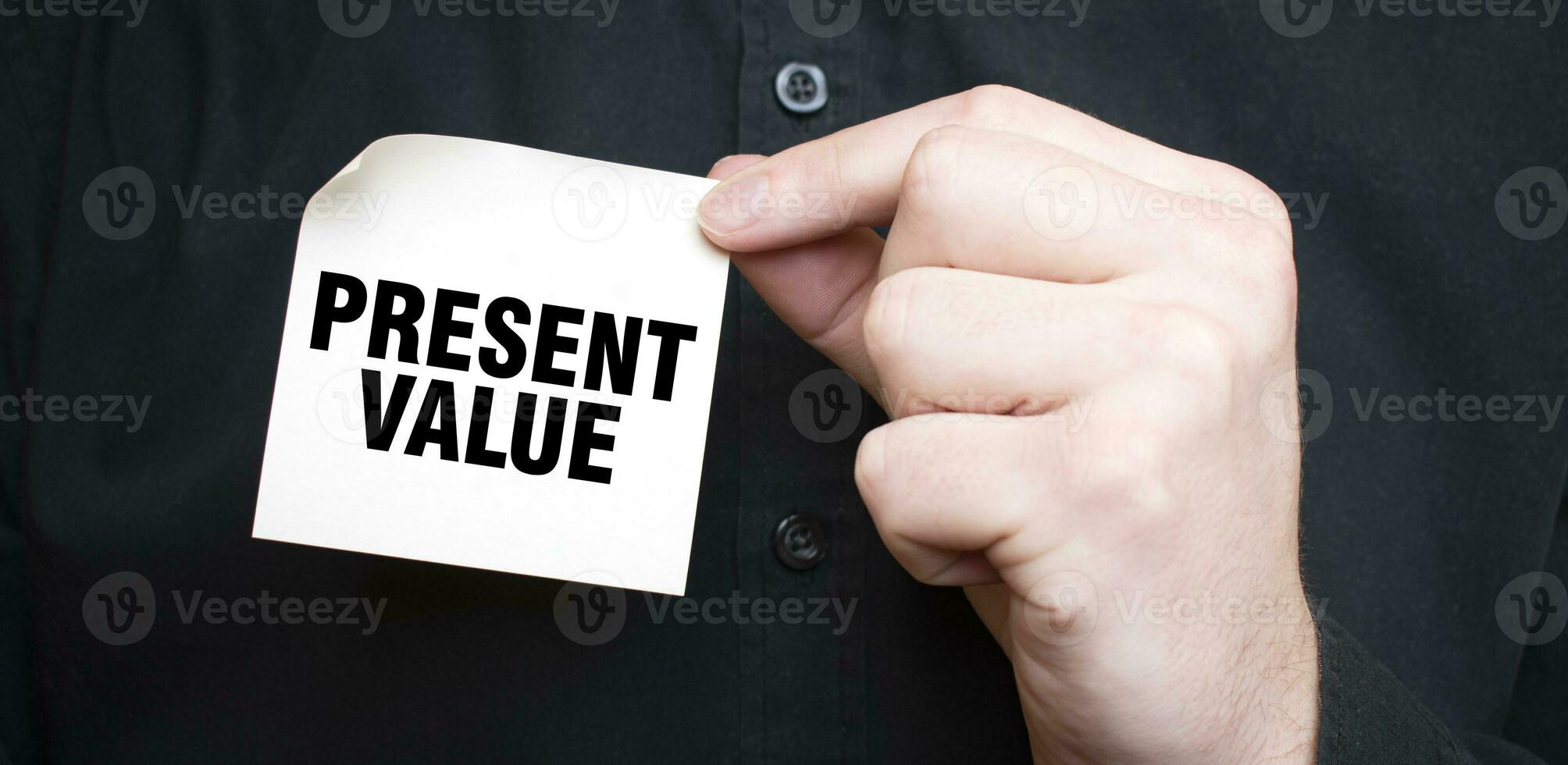 Businessman holding a card with text PRESENT VALUE, business concept photo