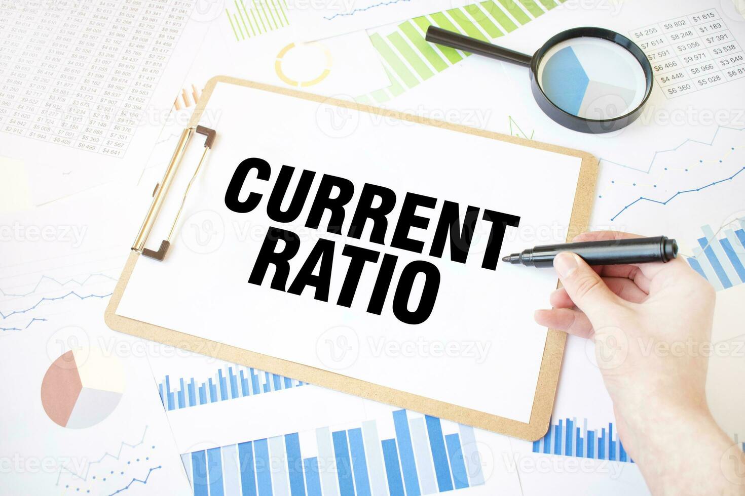 Text CURRENT RATIO on white paper sheet and marker on businessman hand on the diagram. Business concept photo