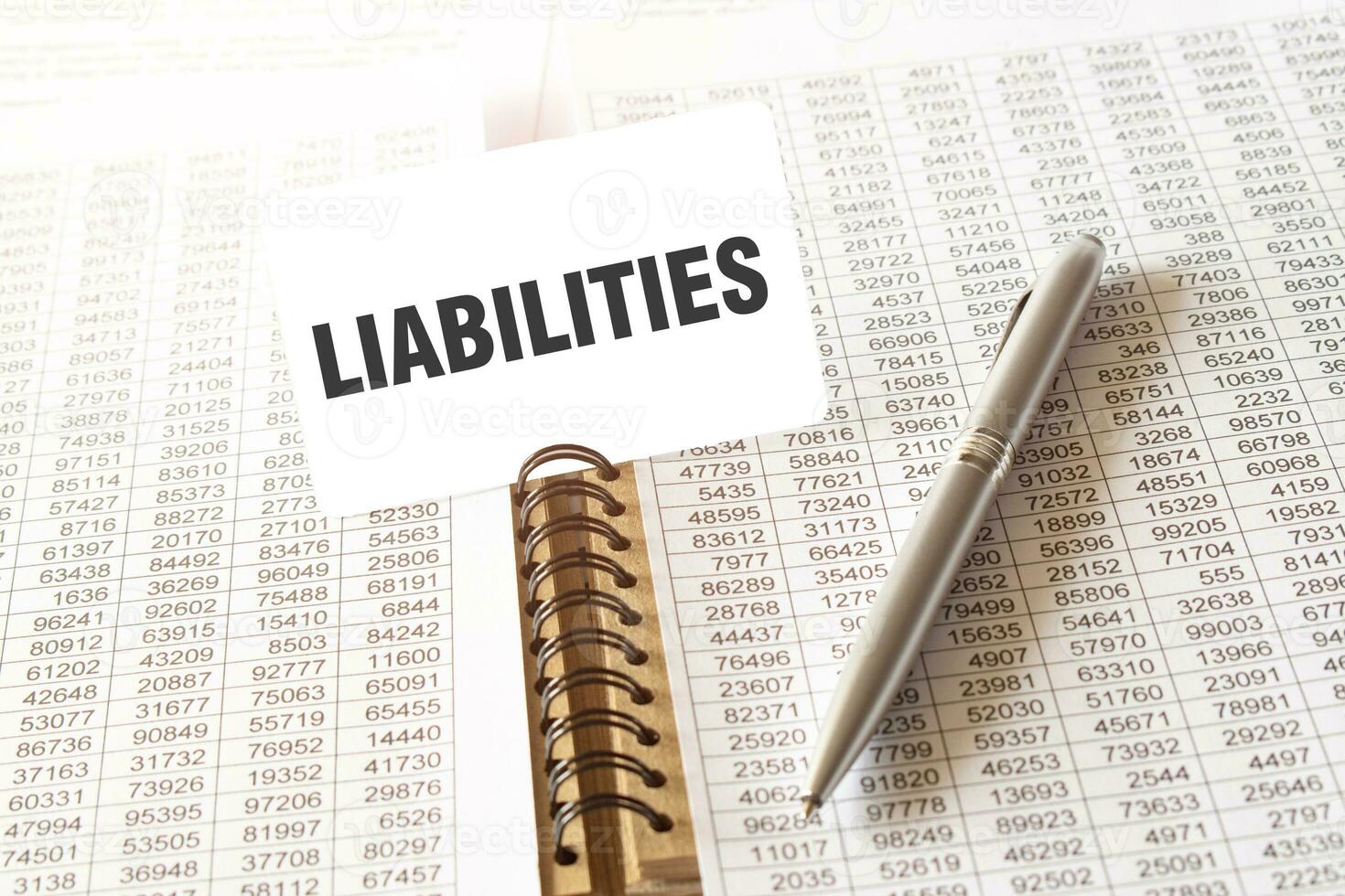 Text LIABILITIES on paper card, pen, financial documentation on table photo