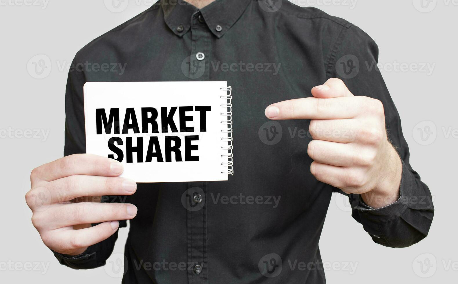 Businessman holding a white notepad with text MARKET SHARE, business concept photo