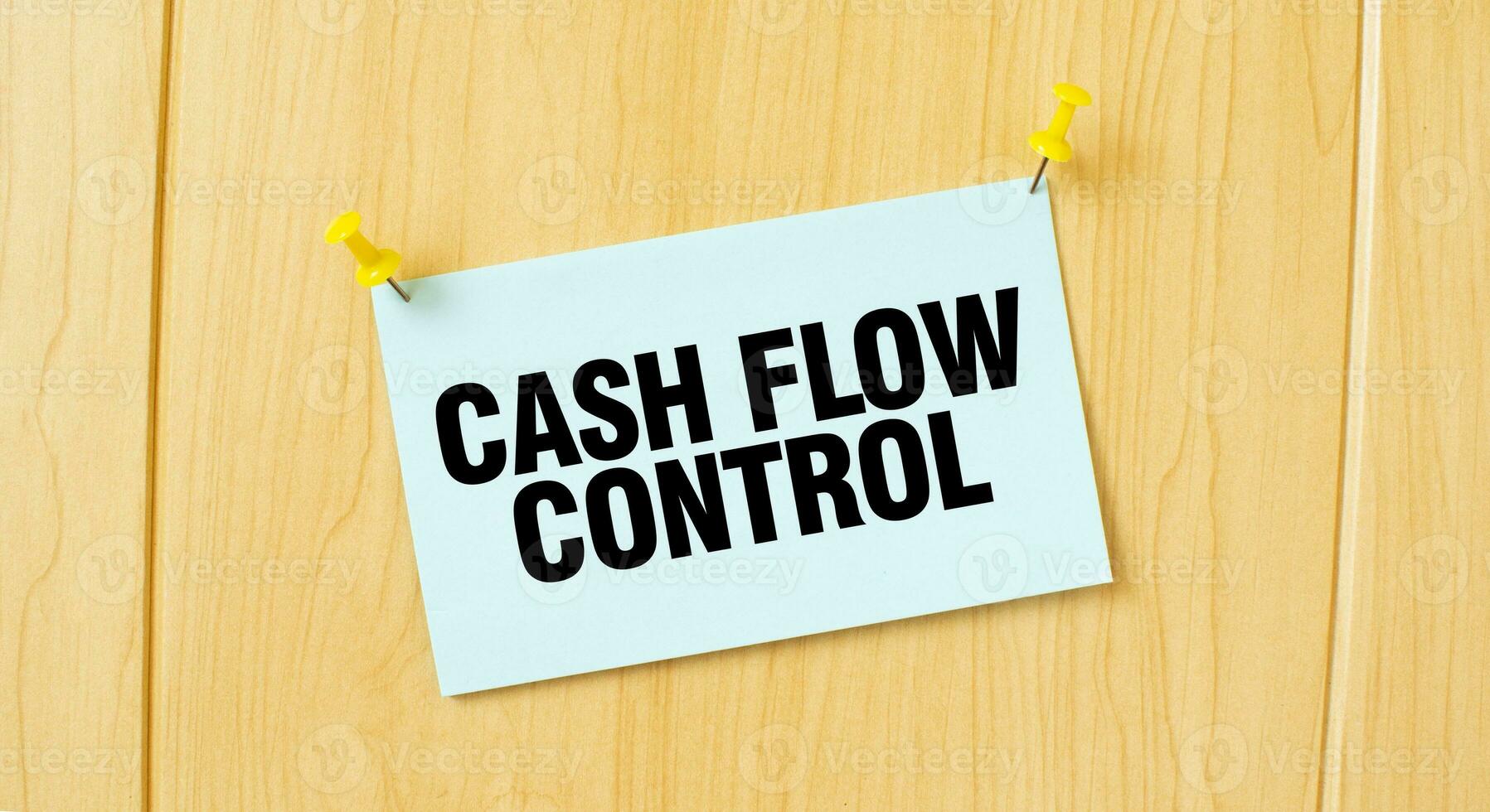 CASH FLOW CONTROL sign written on sticky note pinned on wooden wall photo