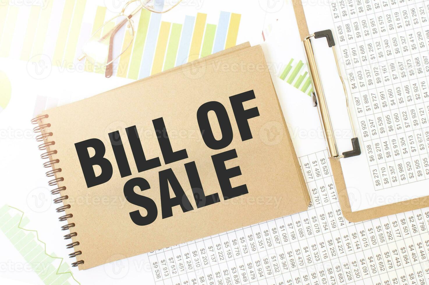 Business up graph on a sheet of craft colour Notepad with BILL OF SALE sign. Notepad on desk with financial documentation photo