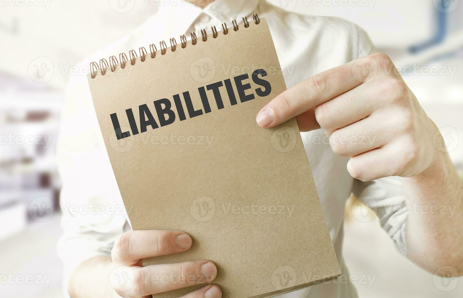 Text LIABILITIES on brown paper notepad in businessman hands in office. Business concept photo