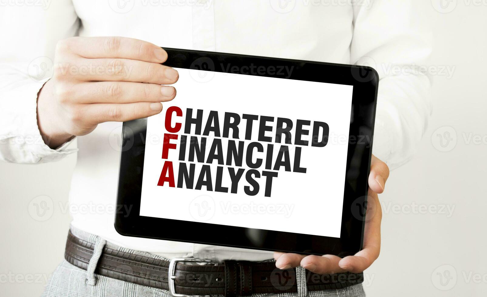 Text CHARTERED FINANCIAL ANALYST on tablet display in businessman hands on the white background. Business concept photo