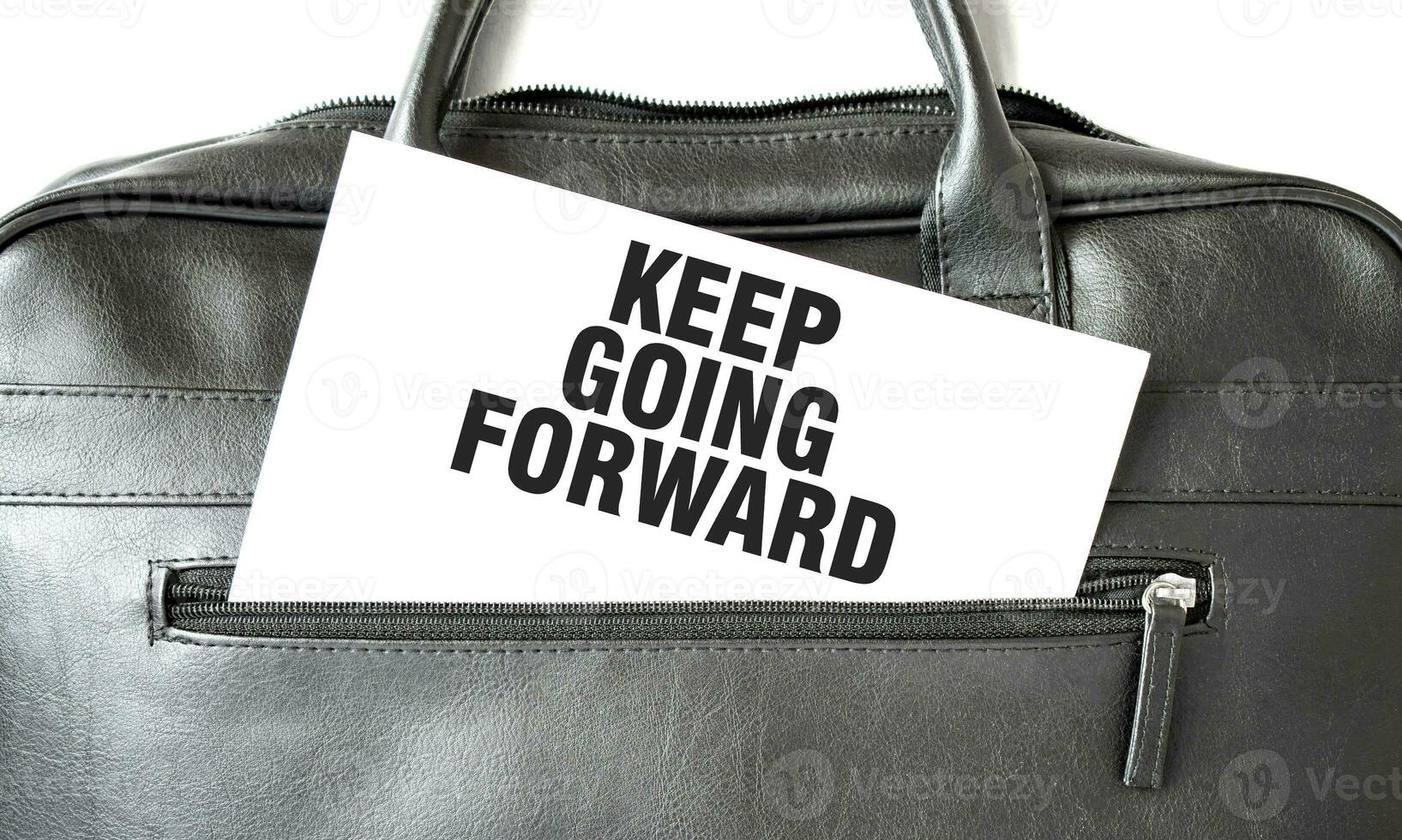 Text KEEP GOING FORWARD writing on white paper sheet in the black business bag. Business concept photo