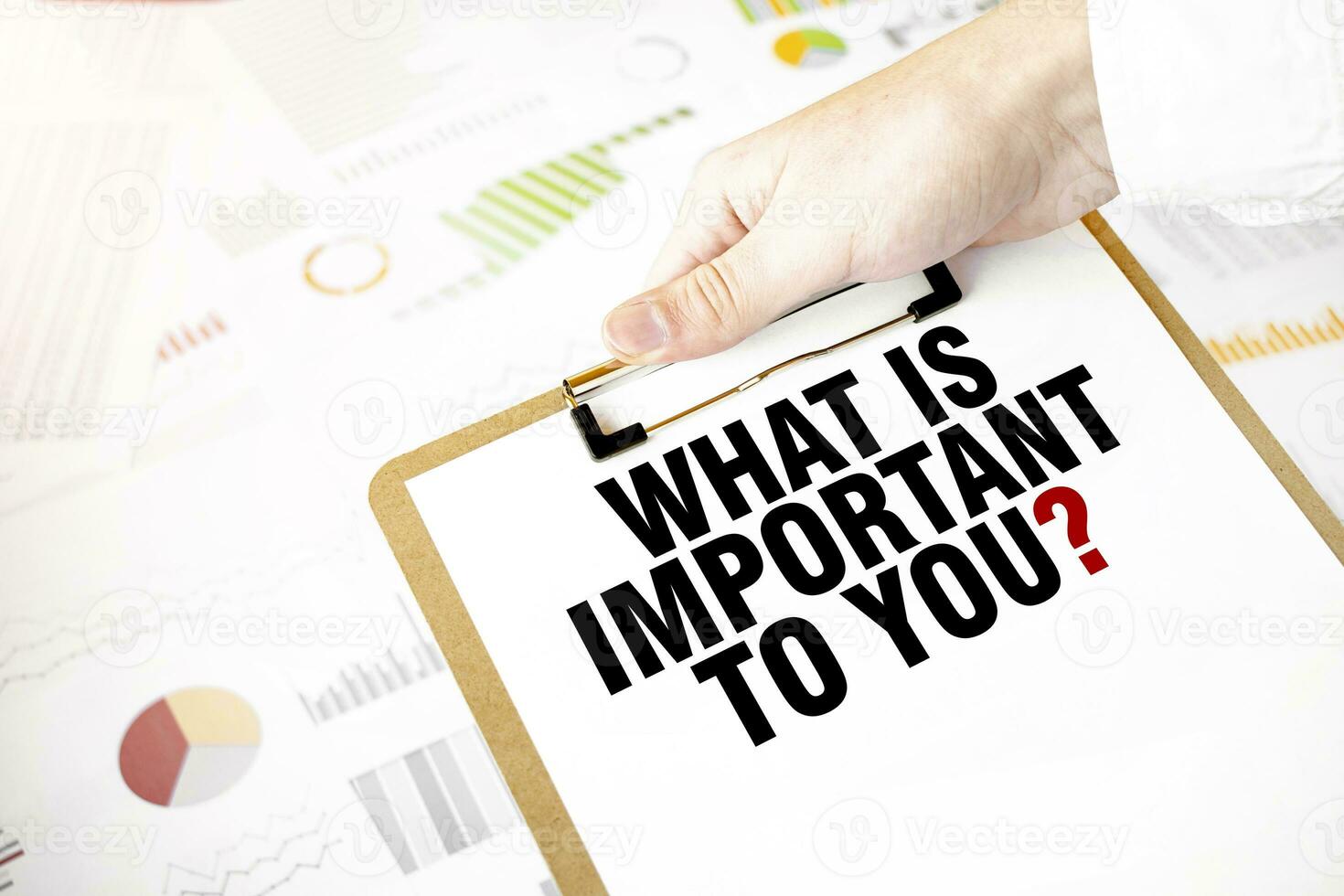 Text WHAT IS IMPORTANT TO YOU on white paper plate in businessman hands with financial diagram. Business concept photo