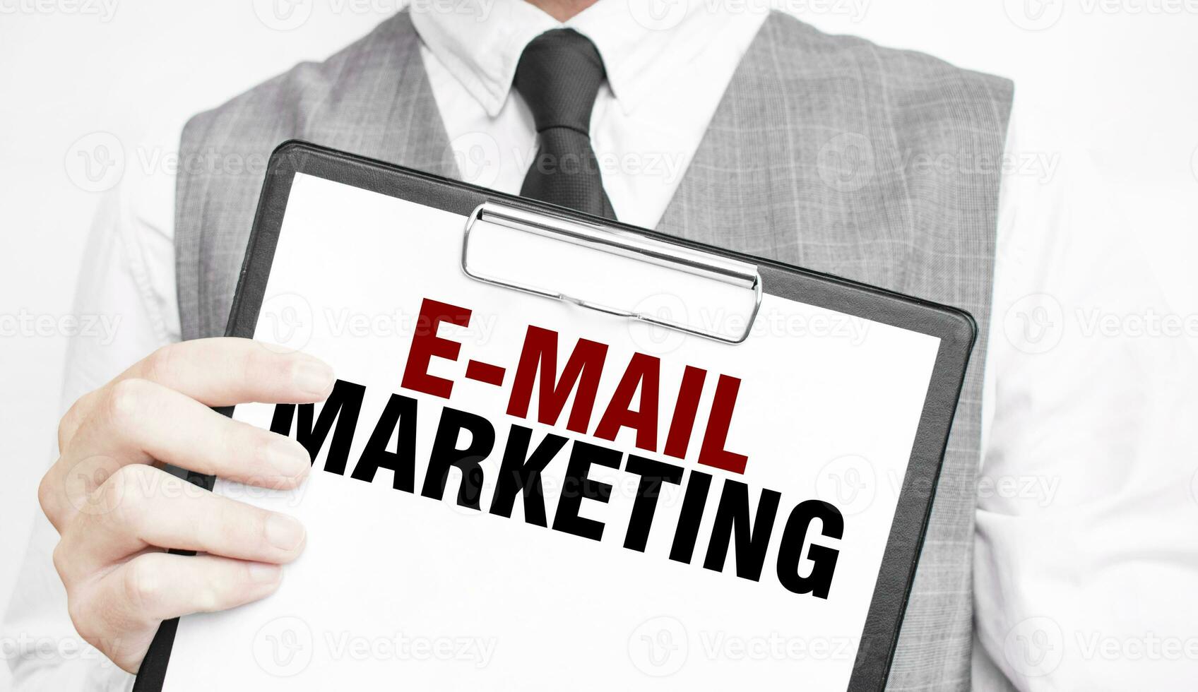 e-mail marketing inscription on a notebook in the hands of a businessman on a gray background, a man points with a finger to the text photo