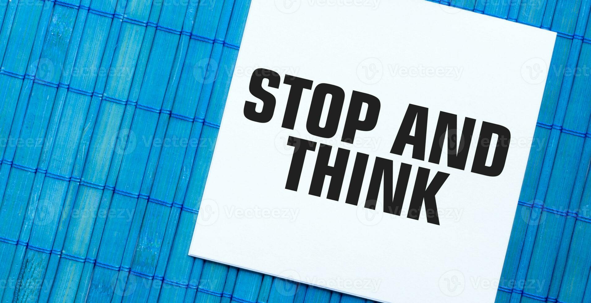blank note pad with STOP AND THINK text on blue wooden background photo
