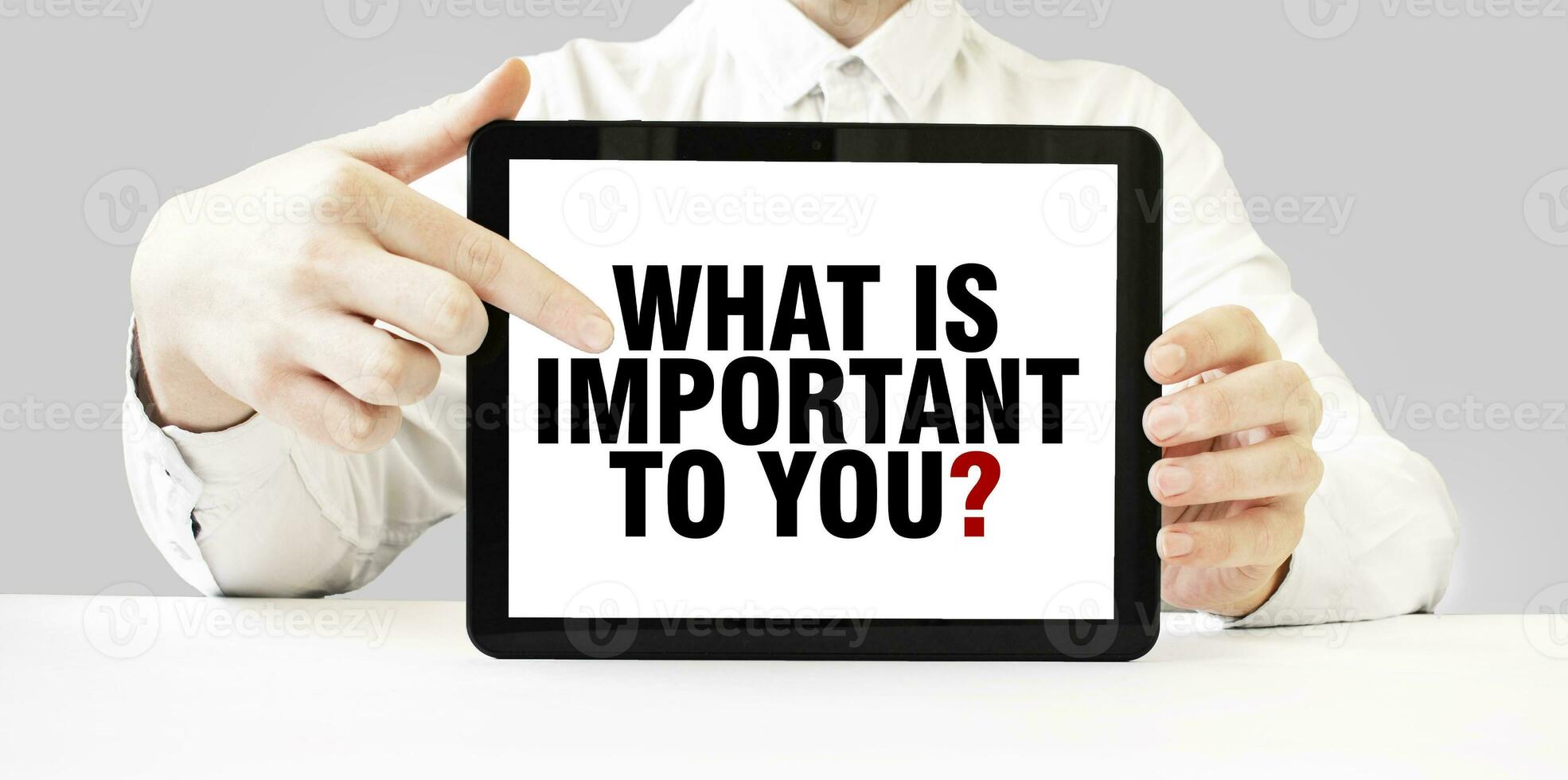 Text WHAT IS IMPORTANT TO YOU on tablet display in businessman hands on the white background. Business concept photo