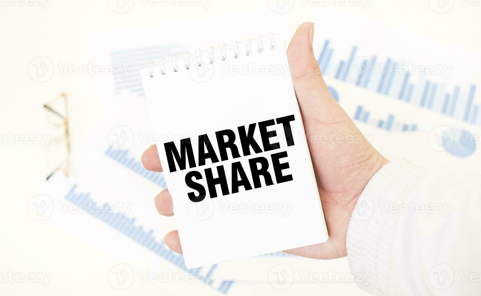 Businessman holding a white notepad with text MARKET SHARE, business concept photo