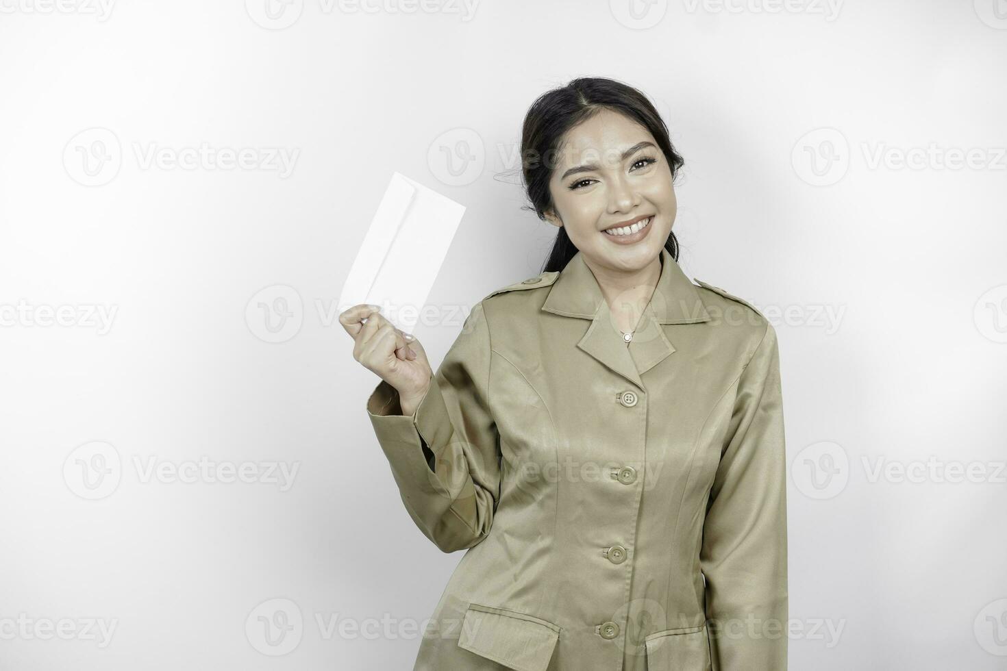 A happy young beautiful Asian worker wearing brown uniform holding an envelope. Indonesian PNS concept. photo