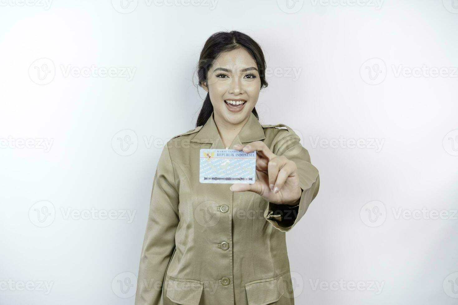 Smiling government worker woman holding Indonesian ID card. PNS wearing khaki uniform. photo