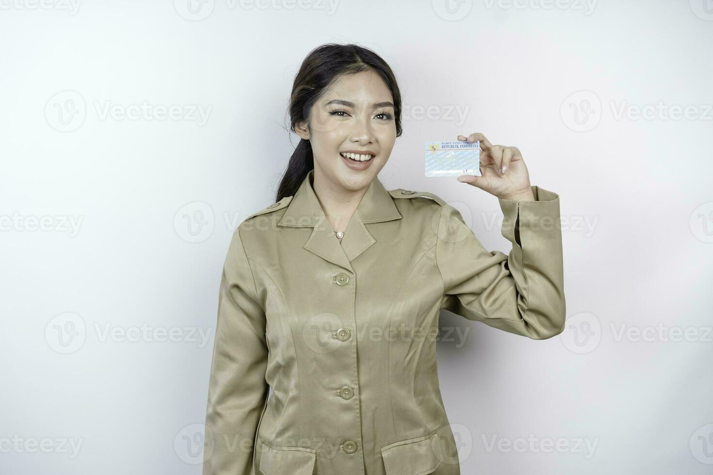 Smiling government worker woman holding Indonesian ID card. PNS wearing khaki uniform. photo