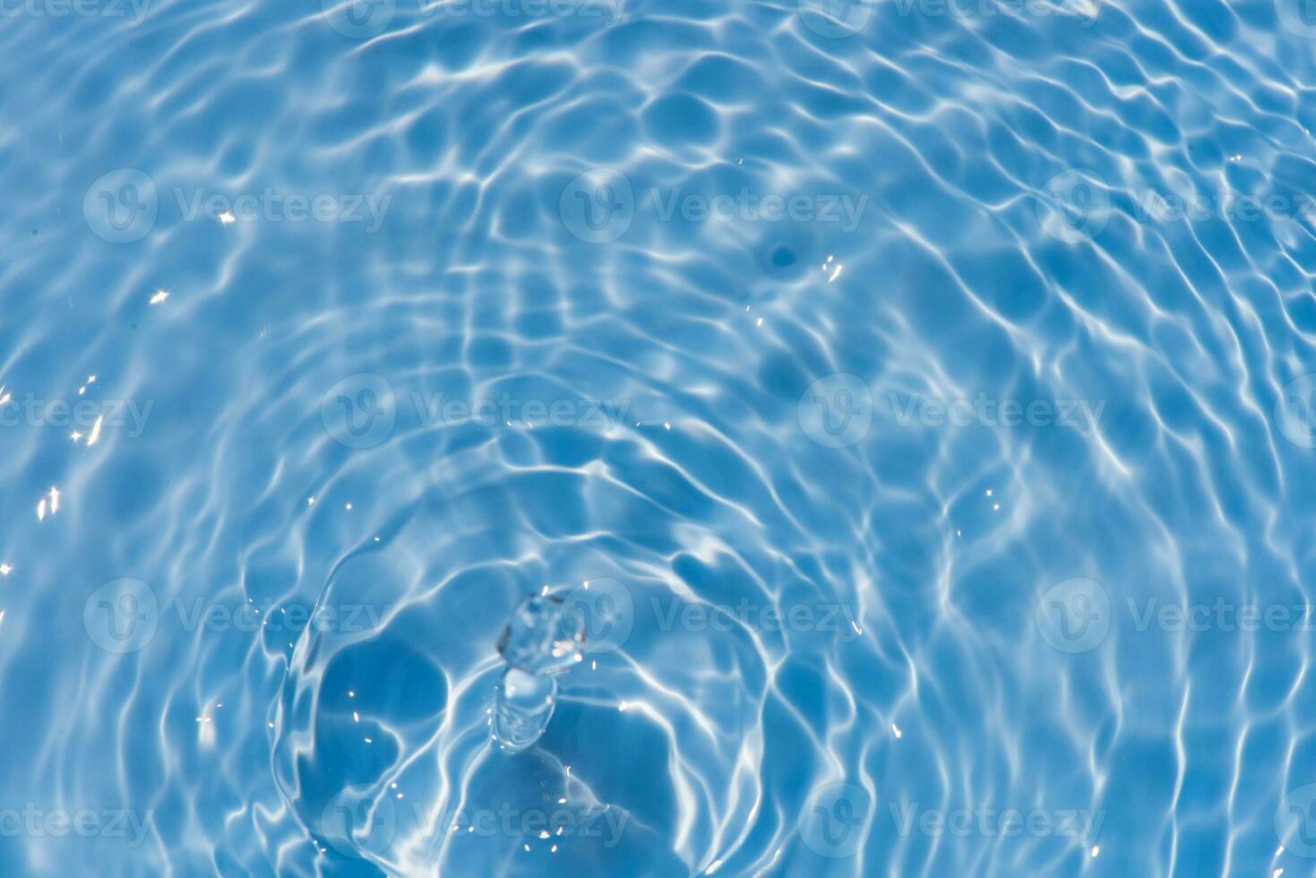 Blue water with ripples on the surface. Defocus blurred transparent blue colored clear calm water surface texture with splashes and bubbles. Water waves with shining pattern texture background. photo