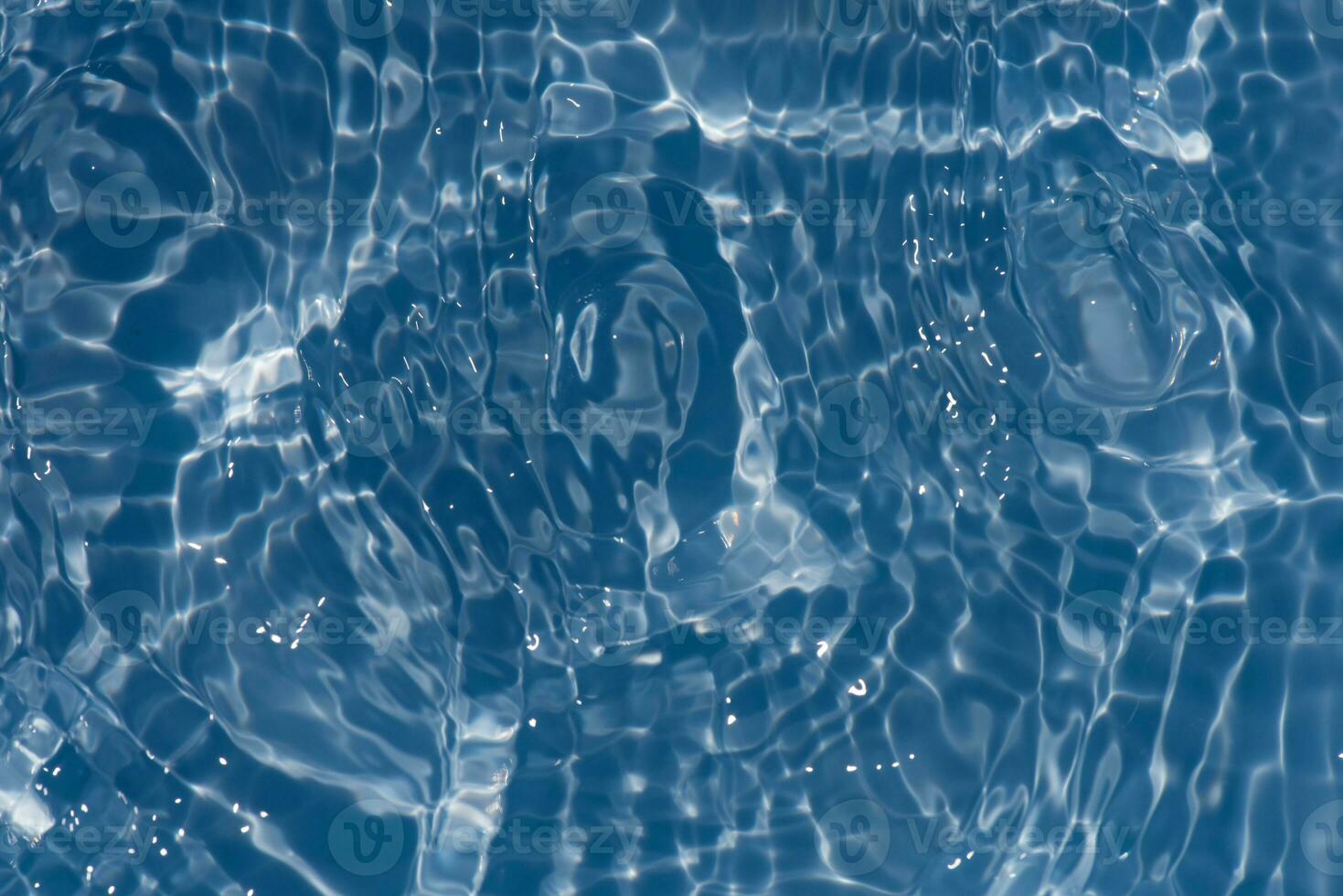 Blue water with ripples on the surface. Defocus blurred transparent blue colored clear calm water surface texture with splashes and bubbles. Water waves with shining pattern texture background. photo