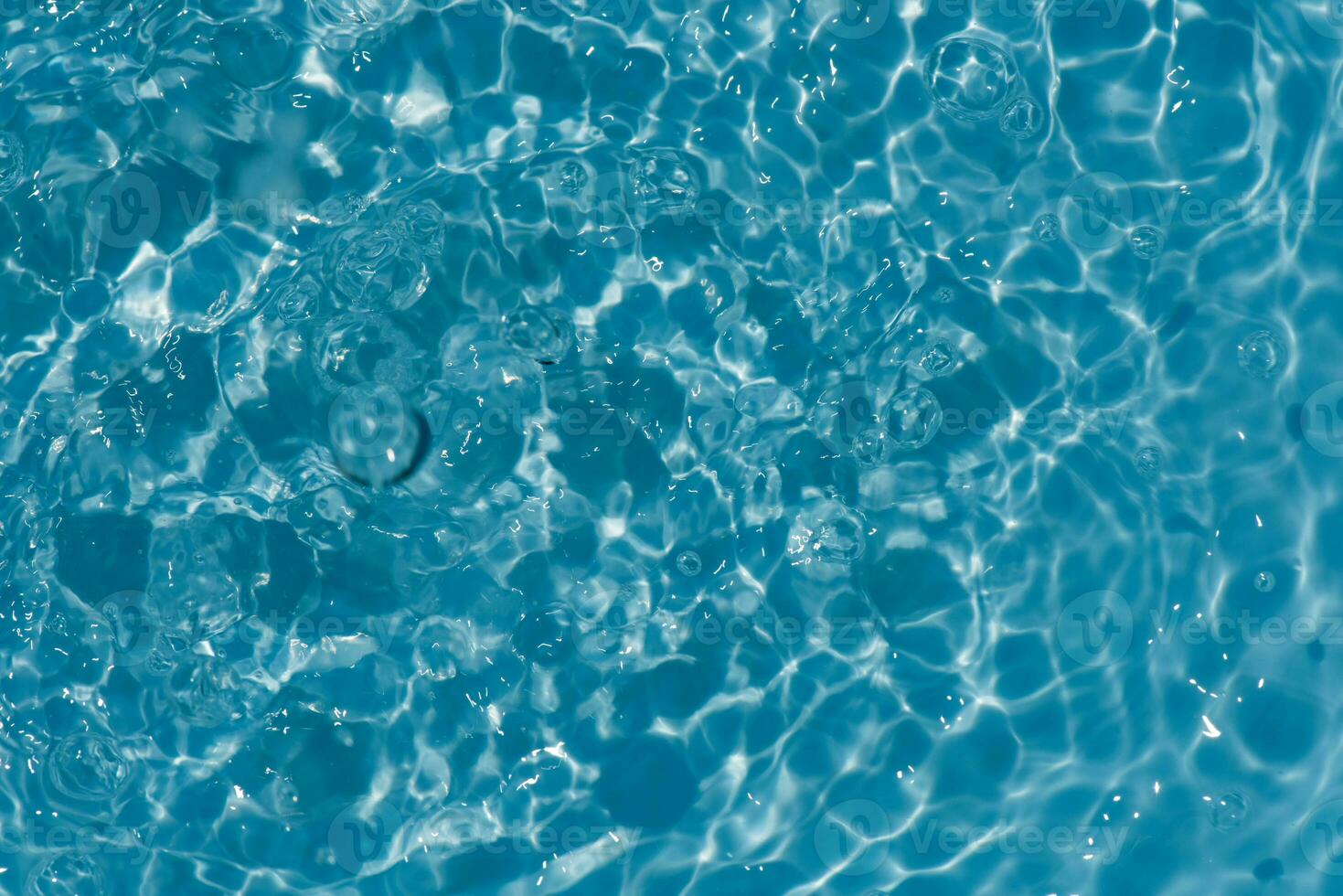 Blue water with ripples on the surface. Defocus blurred transparent blue colored clear calm water surface texture with splashes and bubbles. Water waves with shining pattern texture background. photo