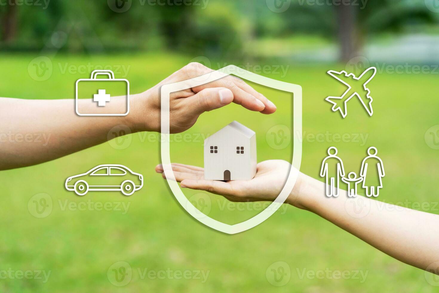 Close-up of hand holding wooden house model with car, family, travel and health insurance icons and concept photo