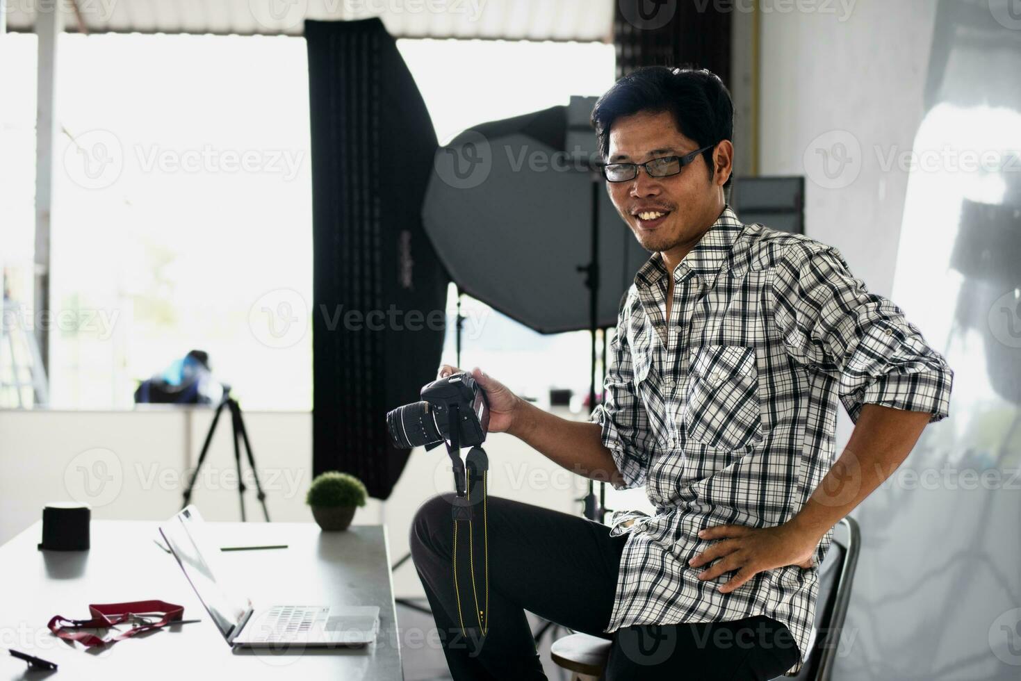 Happy young photographer holding dslr camera in her home office Female photographer smiling cheerfully while working at table Creative man working on new project. photo
