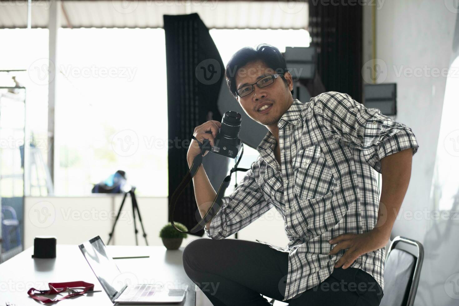 Happy young photographer holding dslr camera in her home office Female photographer smiling cheerfully while working at table Creative man working on new project. photo