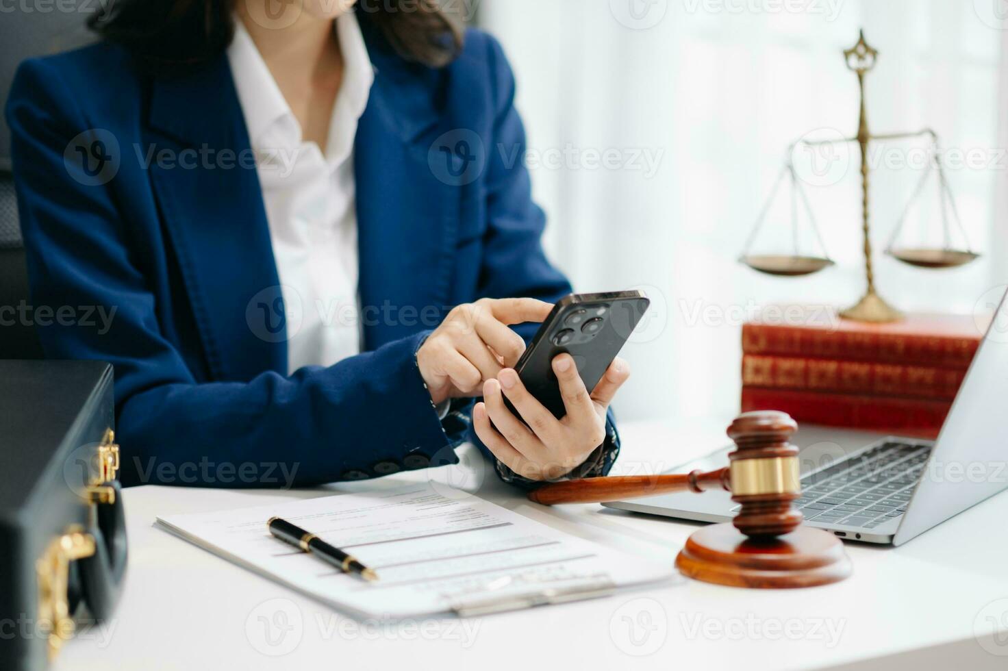 justice and law concept. Female judge in a courtroom the gavel, working with smart phone and laptop and digital tablet computer on white table photo