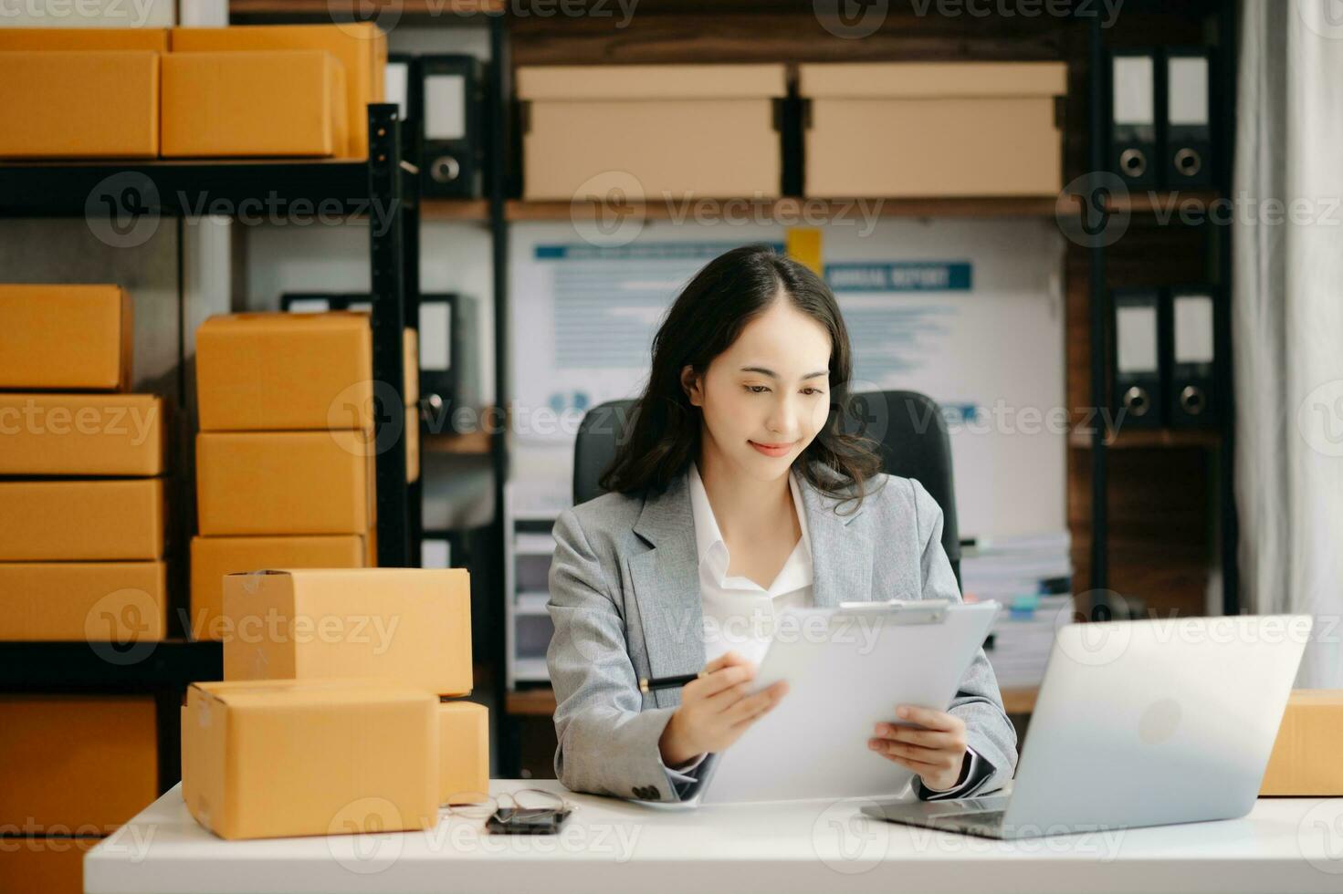 Startup small business SME, Entrepreneur owner woman using smartphone or tablet taking receive and checking online purchase shopping order to preparing pack product box. photo